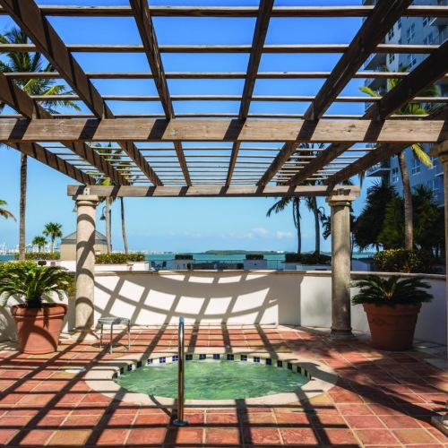 a patio with a bench and a pool in the background