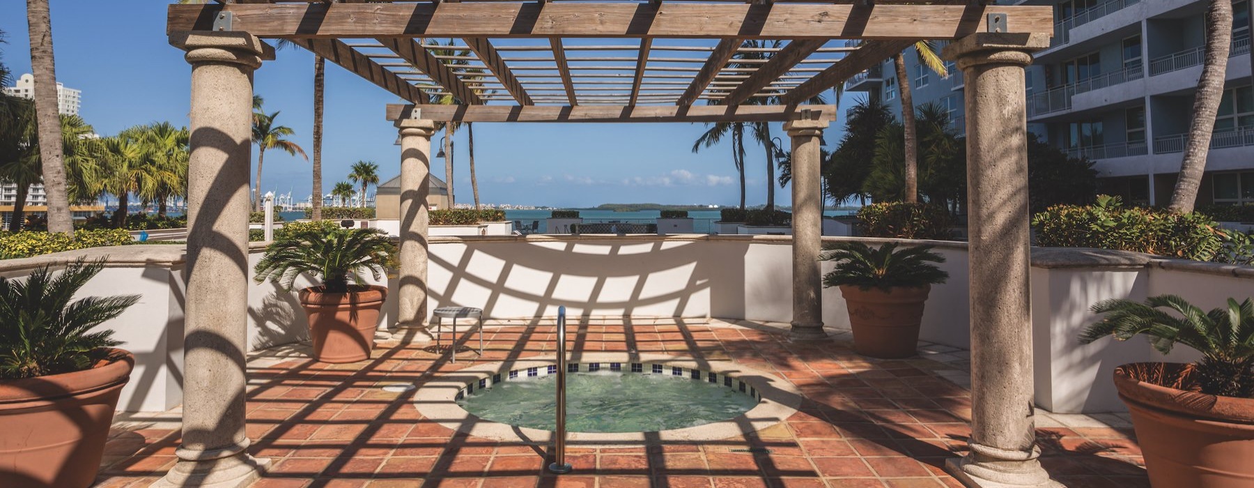 a patio with a bench and a pool in the background