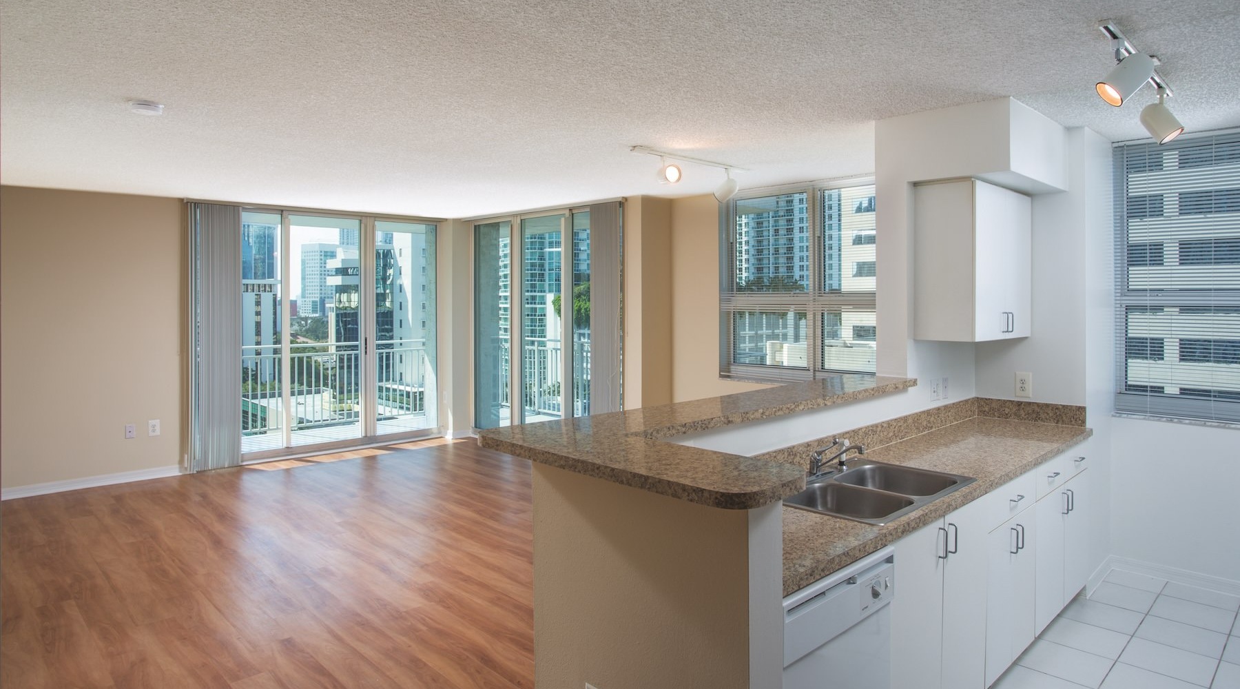an empty kitchen and living room with wood floors nad large windows